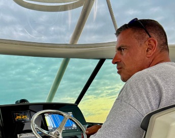 Captain David Grunes at the wheel of a boat, looking out over the water