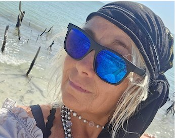 Captain Jamie on a shell beach in sunglasses and a head wrap