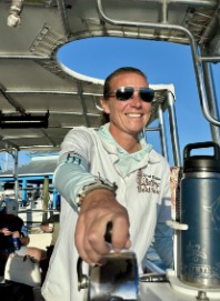 Captain Lauren Malinowski at the helm of a Sand Dollar boat, reaching toward the camera