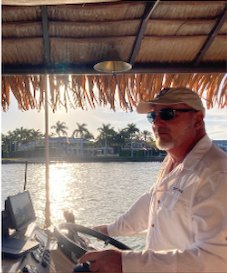 Captain Paul O'Neill steering the tiki boat at golden hour