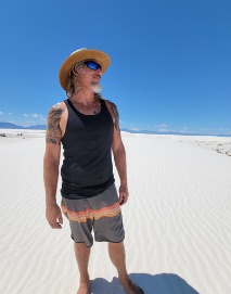 Captain Shawn Palmer in a straw hat and sunglasses on bright white sand dunes