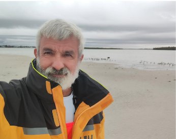 Captain Paul Stancati on an overcast shell beach in foul-weather gear