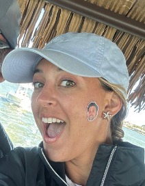 First Mate Veronica smiling in a light-blue cap under the tiki boat's thatched roof
