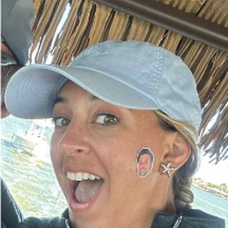First Mate Veronica smiling in a light blue cap under the tiki boat's thatched roof