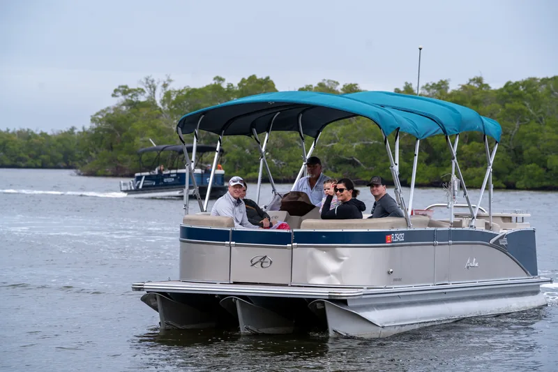 Guests relaxing under the Avalon pontoon's teal biminis while cruising a mangrove channel