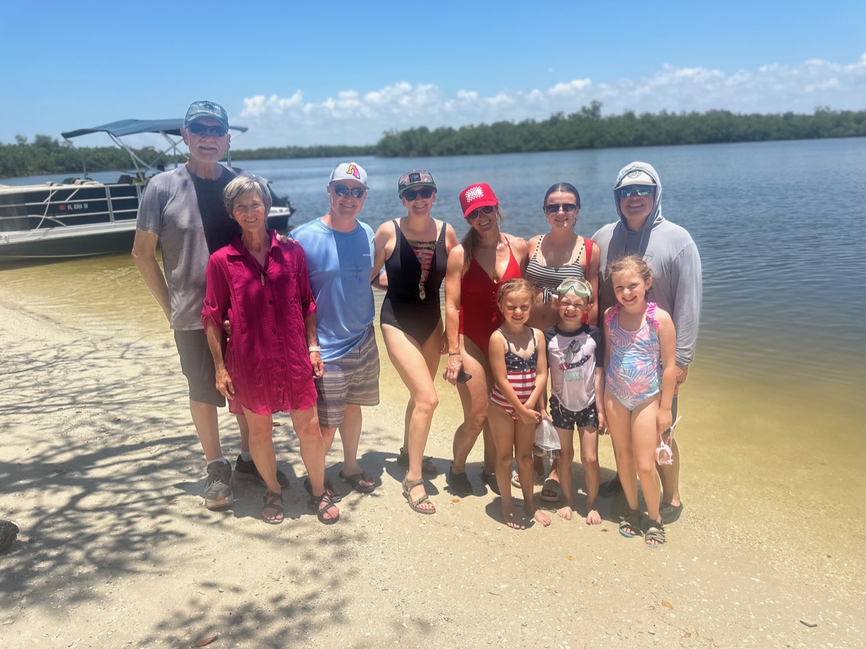 A family on a remote white-sand barrier-island beach beside a Sand Dollar boat near Marco Island, Florida