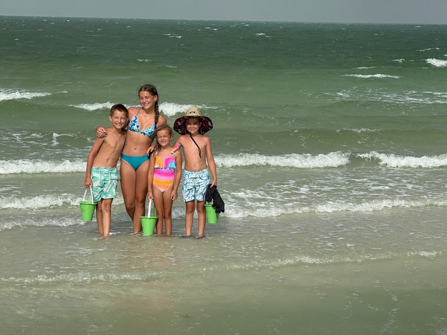 Kids wading in the Gulf shallows with buckets on a Sand Dollar island excursion near Marco Island, Florida