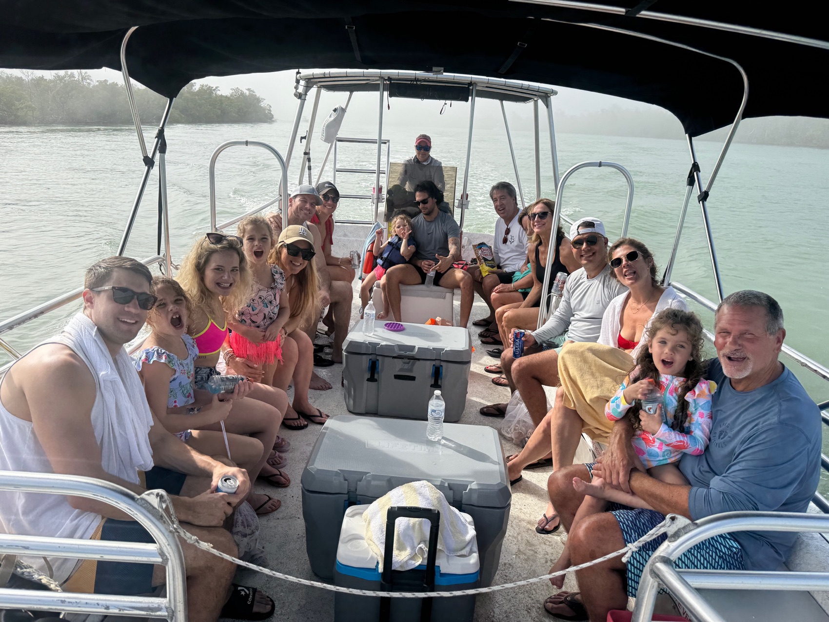 A multigenerational family smiling aboard their private Sand Dollar pontoon charter on bright blue water near Marco Island, Florida