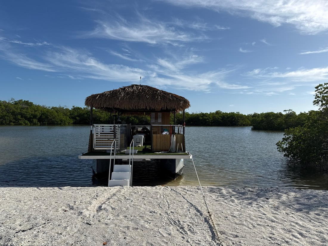 The Sand Dollar tiki boat beached on a Ten Thousand Islands sandbar under blue Florida sky