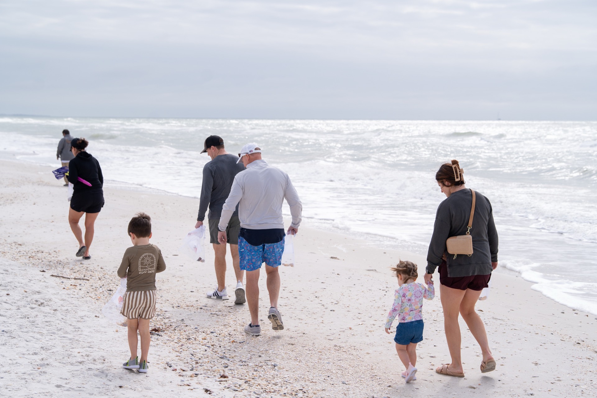 A multigenerational family walking a shell-covered white-sand Gulf beach on a Sand Dollar shelling tour near Marco Island, Florida