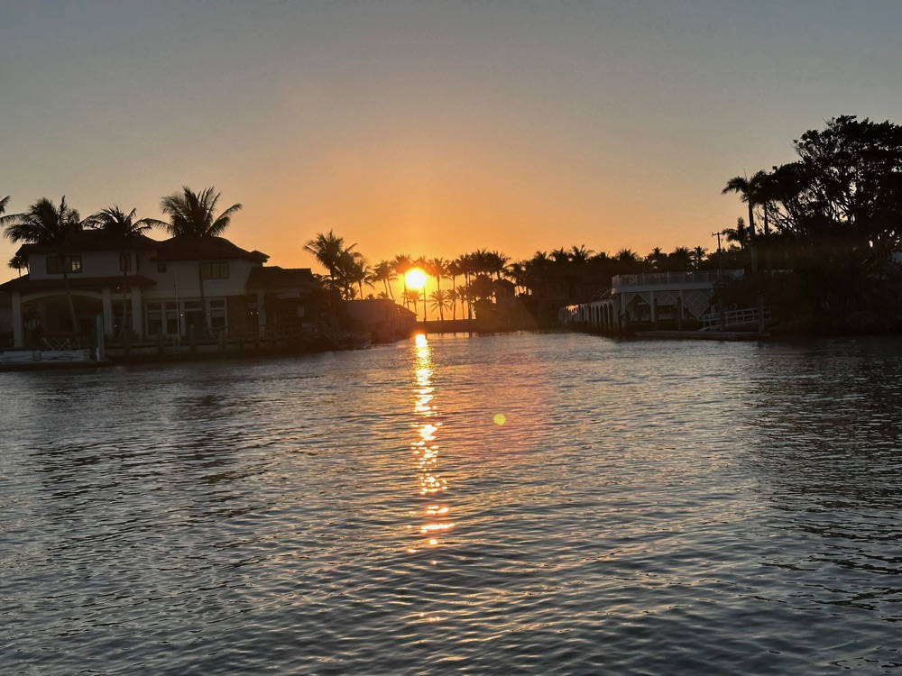 Golden sunset reflecting on a Naples waterway lined with palm trees and luxury waterfront homes, Marco Island area