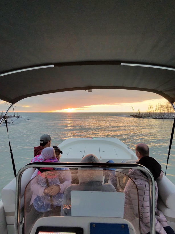 A family watching a golden sunset from the bow of a Sand Dollar boat near Marco Island, Florida